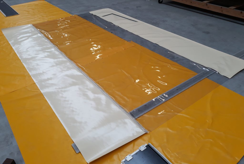 Panneaux de bâche jaune et grise à plat en atelier, en cours de confection