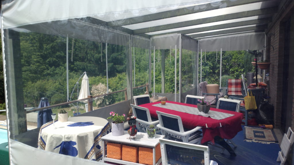 Véranda fermée par des parois bâchées transparentes, tables dressées à l'intérieur