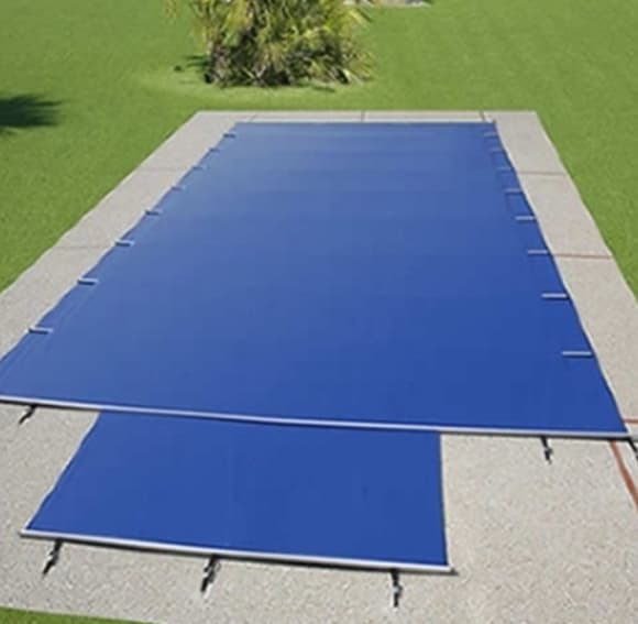 Bâche à barres bleue sur une piscine rectangulaire dans un jardin