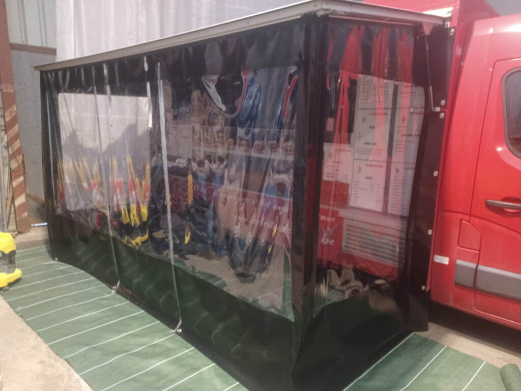 Remorque de vente rouge fermée par des parois bâchées transparentes