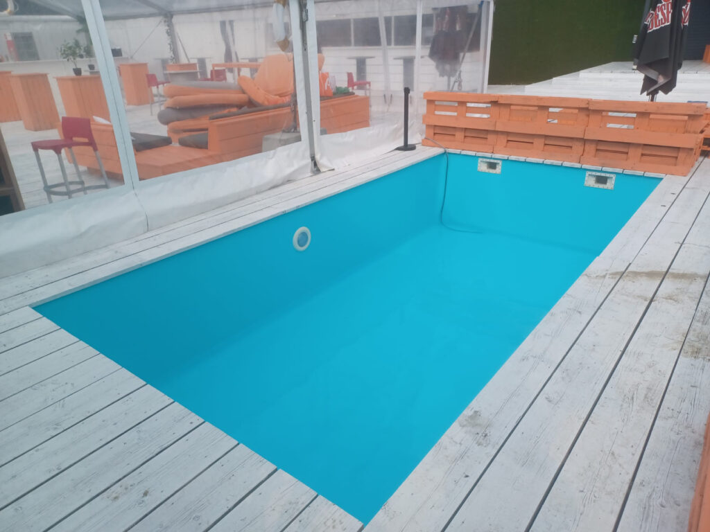 Piscine intérieure à liner turquoise bordée d'une terrasse en bois